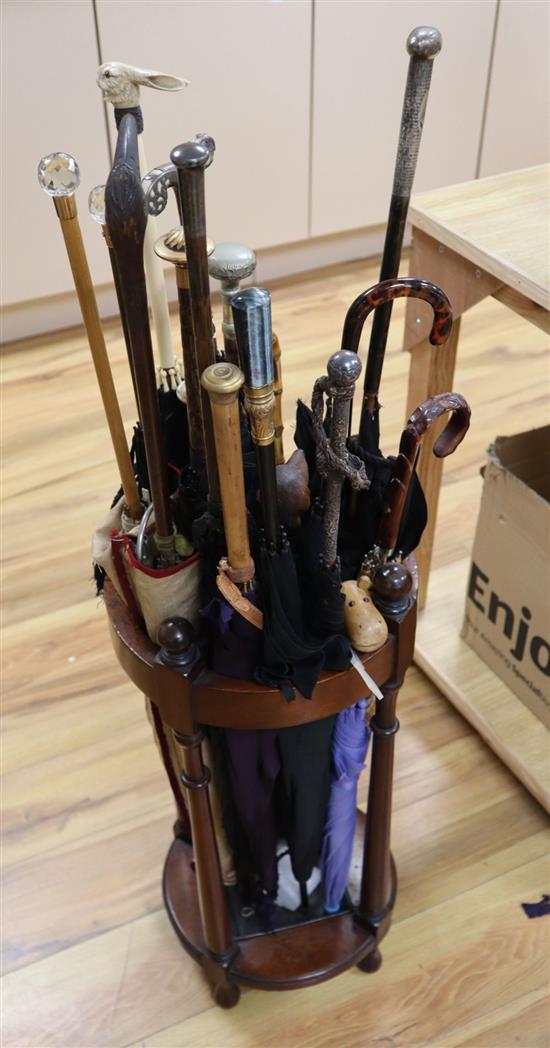 A collection of novelty and decorative parasols, contained within a cylindrical mahogany stick stand